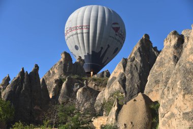 Kapadokya, Türkiye'de sıra dışı kayalık manzaranın panoramik manzarası. Renkli sıcak hava balonları Kapadokya bölgesinin derin kanyonları, vadileri ve peri bacaları üzerinde gökyüzünde uçuyor. 