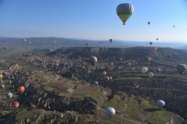 Kapadokya, Türkiye'de sıra dışı kayalık manzaranın panoramik manzarası. Renkli sıcak hava balonları Kapadokya bölgesinin derin kanyonları, vadileri ve peri bacaları üzerinde gökyüzünde uçuyor.
