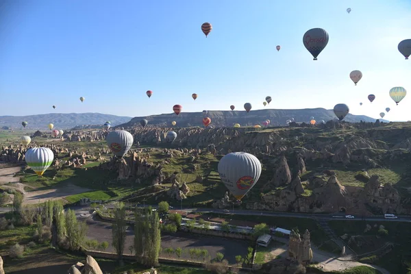 Kapadokya, Türkiye'de sıra dışı kayalık manzaranın panoramik manzarası. Renkli sıcak hava balonları Kapadokya bölgesinin derin kanyonları, vadileri ve peri bacaları üzerinde gökyüzünde uçuyor. 