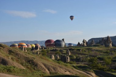 Kapadokya, Türkiye'de sıra dışı kayalık manzaranın panoramik manzarası. Renkli sıcak hava balonları Kapadokya bölgesinin derin kanyonları, vadileri ve peri bacaları üzerinde gökyüzünde uçuyor. 