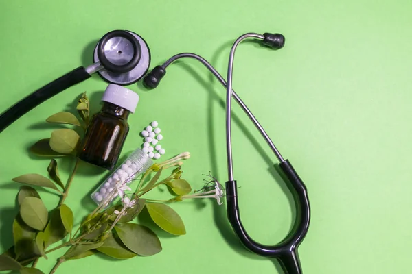 Stetoskoplar ve nane arka plan üzerinde yaprakları homeopatik globule hapları ve sıvı cam şişe üst görünümü