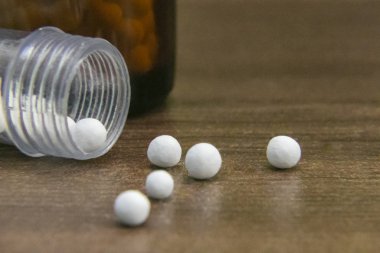 Ahşap arka plan üzerinde dağınık homeopatik globüller ve şişe yakın görünüm görüntüsü. Homeopati ilacı