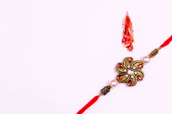 Raksha Bandhan - Yaratıcı kumkum ve pirinç tanecikli beyaz arka planda güzel Rakhi