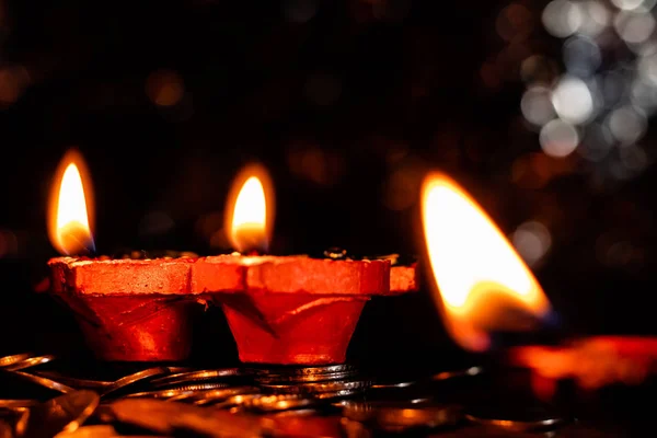 前景のぼやけた炎に焦点を当てた土製のテラコッタ製のランプのペア Diwaliのコンセプトのためのコインの山 — ストック写真