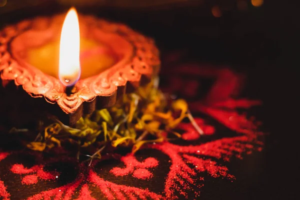 Diwali 'de kırmızı Rangoli tasarımı ve çiçekli güzel bir toprak lambası. Sadakat ve Diwali kavramı.