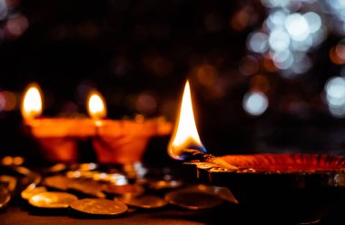 Diwali dekorasyon konseptinde parlayan toprak toprak terasotta lambalarının yakınlaştırılması ve yerde bozuk paralar