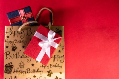 Doğum günü hediyesi konsepti. Kırmızı ve mavi hediye kutularının üst görünümü ve kırmızı zemin üzerinde doğum günü baş harfleri olan fotokopi alanı olan çanta