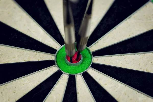 three darts thrown at the bulls eye of a dartboard