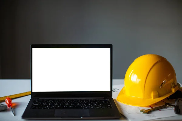 laptop and construction items, yellow helmet, apartment plan on the table, text, construction concept nobody