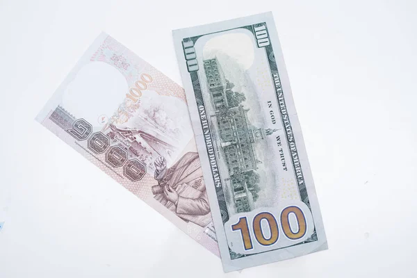 Une pile de baht thaïlandais et cent dollars sur une table blanche . — Photo