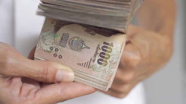 Close-up handen tellen van thousansds Thaise Baht geld. Close-up menselijk tellen Thaise bankbiljet, Richman tellen en het houden van honderd. Baht rekeningen op tafel. — Stockfoto