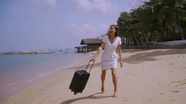 在美丽的海边，一个手提箱走的女商人。自由职业者概念，期待已久的休闲理念. — 图库视频影像