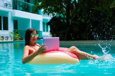 bir laptop ile havuzda şişme daire kız, freelancing ve rekreasyon kavramı.