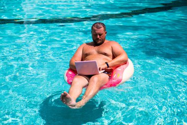 Hayalindeki iş, genç bir adam su şişme bir daire, adam su şişme halkası üzerinde bir dizüstü bilgisayar ile bir bilgisayar ile