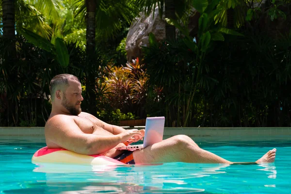 Dream job, a young man with a computer in the water on an inflatable circle,Man with a laptop on inflatable ring in the water