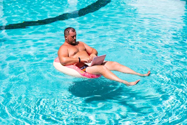 Drömjobb, en ung man med en dator i vattnet på en uppblåsbar cirkel, mannen med en laptop på uppblåsbar ring i vattnet — Stockfoto