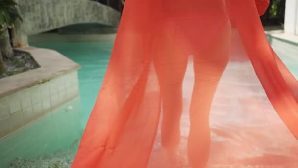 Hermosa chica en un vestido largo de color rosa nada en la piscina. Encantadora morena en un vestido largo rosa posa para la cámara en una piscina azul . — Vídeo de stock