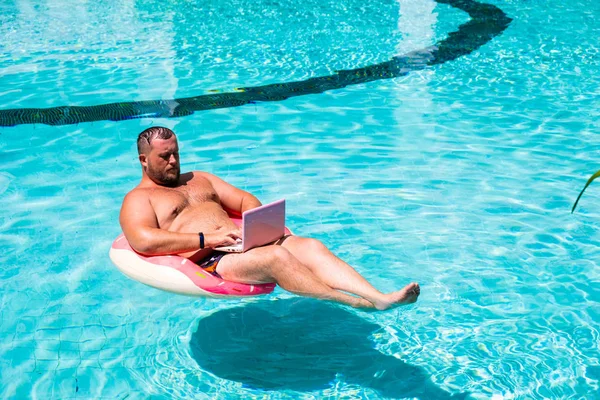 Dream job, a young man with a computer in the water on an inflatable circle,Man with a laptop on inflatable ring in the water