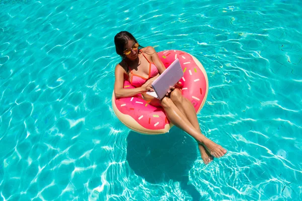 Jonge vrouwelijke freelancer met een tablet in een opblaasbare cirkel in het zwembad. Luchtzicht — Stockfoto