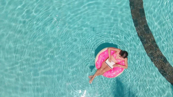 美しい女性とインフレータブルプールでドーナツの形でリングを泳ぐ. — ストック写真