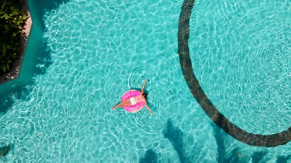 美しい女性とインフレータブルプールでドーナツの形でリングを泳ぐ. — ストック写真