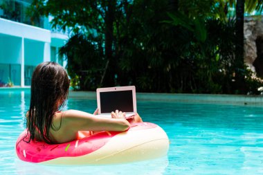 bir laptop ile havuzda şişme daire kız, freelancing ve rekreasyon kavramı.