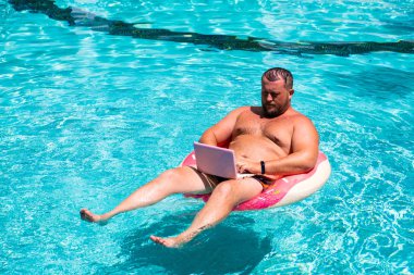 Hayalindeki iş, genç bir adam su şişme bir daire, adam su şişme halkası üzerinde bir dizüstü bilgisayar ile bir bilgisayar ile