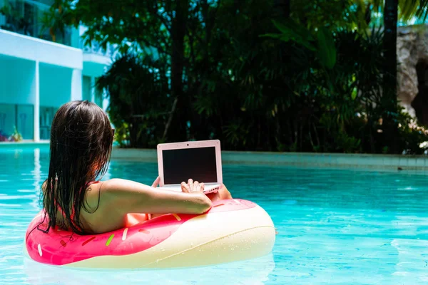 Girl in the inflatable circle in the pool with a laptop, the concept of freelancing and recreation. — Stock Photo, Image