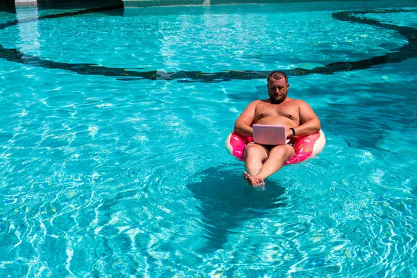 Mannelijke freelancer met een laptop op rubber ring in het water — Stockfoto