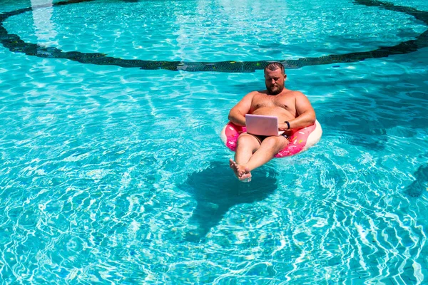 Male businessman with a laptop on rubber ring in the water — Stock Photo, Image