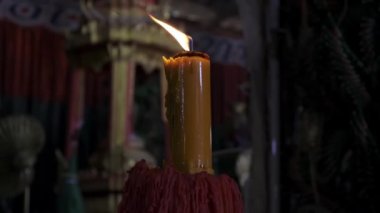 Tapınakta siyah bir arka plan üzerinde yanan mum.