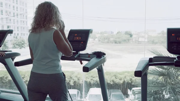 Mujer mayor haciendo caminadora en el gimnasio y hablando por teléfono — Foto de Stock