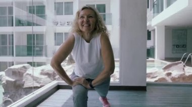 Yaşlı kadın spor salonunda çömelmiş. Yaşlı kadın Yaşlı kadın spor salonunda bir spor egzersizleri yapar