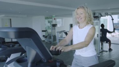 Pattaya, Tayland - 15 Mayıs 2019: spor salonunda koşu bandında kulaklıkla müzik dinleyen yaşlı kadın, yakın çekim.