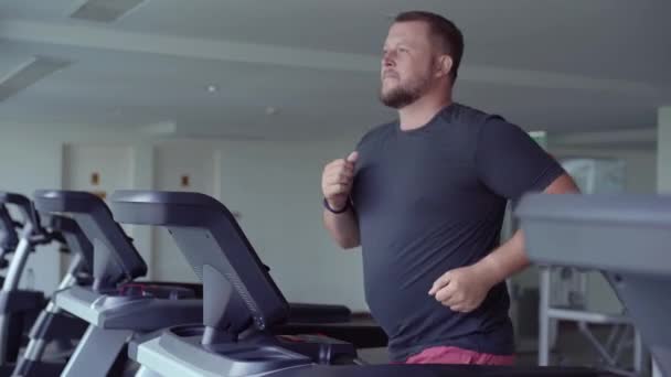 胖胖的男人在跑道上行走,在健身房跑步机上热身. — 图库视频影像