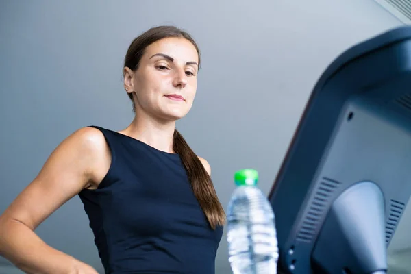 Hermosa chica de fitness corriendo y beber agua en la cinta de correr en el gimnasio — Foto de Stock