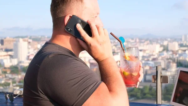 Man praten op de telefoon en werken op een computer in een café met een prachtig uitzicht — Stockfoto