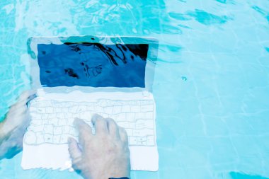 Erkek su altında minibilgisayar üzerinde çalışır. Havuzun dibindeki mini bilgisayar. İş yerinde bir sürü iş kavramı. Bulanıklaştırma soyut arka plan.