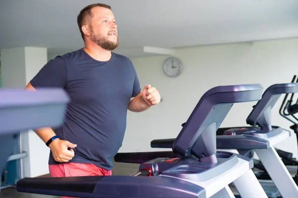 tombul adam koşu pistinde yürüyüş, spor salonu koşu bandı üzerinde ısınma.