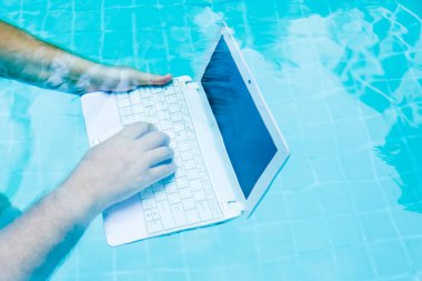 Erkek su altında minibilgisayar üzerinde çalışır. Havuzun dibindeki mini bilgisayar. İş yerinde bir sürü iş kavramı. Bulanıklaştırma soyut arka plan.