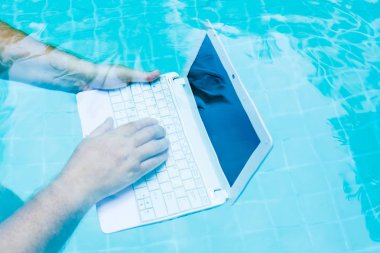 Erkek su altında minibilgisayar üzerinde çalışır. Havuzun dibindeki mini bilgisayar. İş yerinde bir sürü iş kavramı. Bulanıklaştırma soyut arka plan.