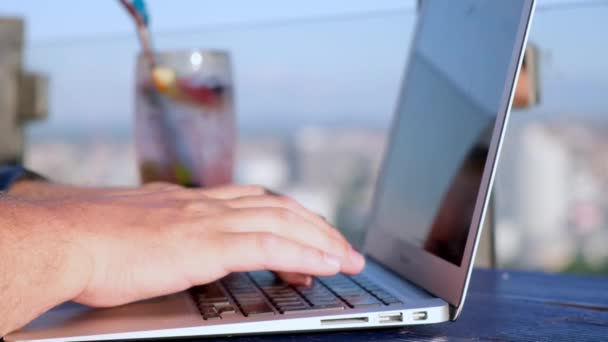 Primer plano retrato de la mano masculina escribiendo en el ordenador portátil en la cafetería exterior . — Vídeos de Stock