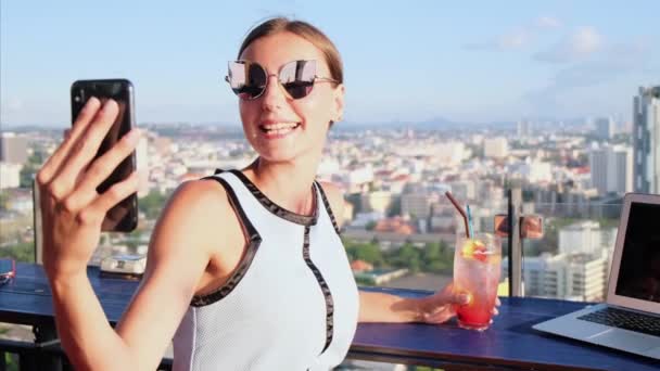 Selfie aantrekkelijk meisje in een café op het dak met panoramisch uitzicht. — Stockvideo