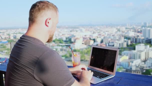 Чоловік працює на комп'ютері в кафе з красивим видом — стокове відео