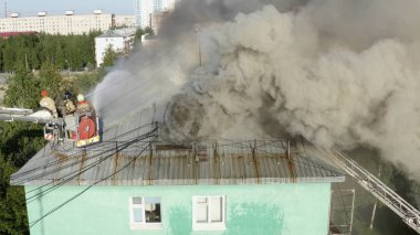 Nizhnevartovsk, Rusya - 1 Temmuz 2019: İtfaiyeciler yüksek katlı bir binanın çatısında çıkan yangını söndürdü