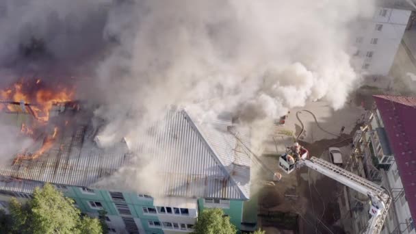 Нижневартовск, Россия - 1 июля 2019 года: пожарные тушат пожар на крыше жилого многоэтажного дома — стоковое видео