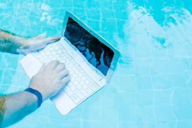 Erkek su altında minibilgisayar üzerinde çalışır. Havuzun dibindeki mini bilgisayar. İş yerinde bir sürü iş kavramı. Bulanıklaştırma soyut arka plan.