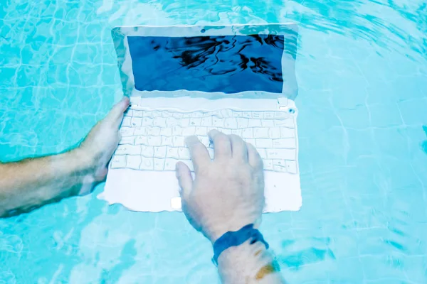 Male works on minicomputer under water. Minicomputer at the bottom of the pool. The concept of a lot of work at work. Blur abstract background.