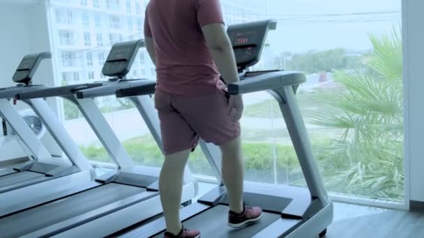 Pummeliger Mann läuft auf Laufstrecke, wärmt sich auf Fitness-Laufband auf. — Stockvideo
