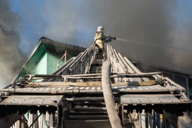 Nizhnevartovsk, Rusya - 1 Temmuz 2019: Bir konutun çatısı yanıyor. İtfaiyeciler bir konut yüksek katlı binanın çatısında bir yangın söndürmek.